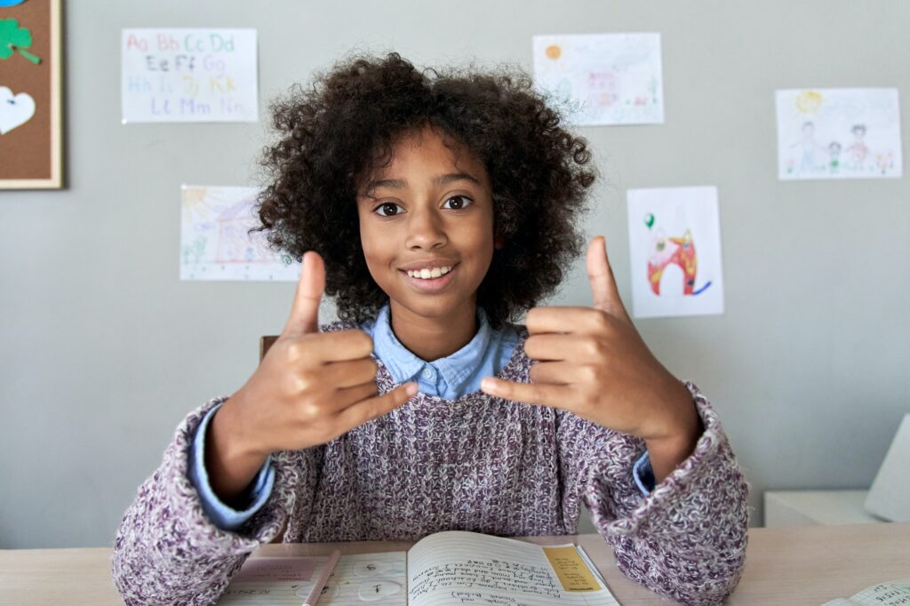 African deaf kid girl showing sign language gesture looking at camera.
